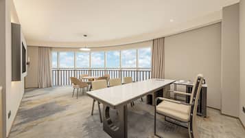 A hotel room with a large window, a dining table, and several chairs.