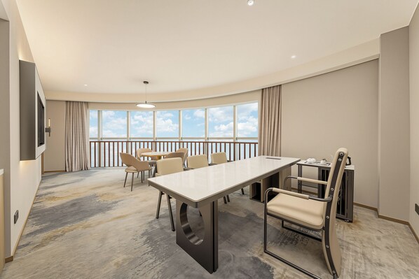 A hotel room with a large window, a dining table, and several chairs.