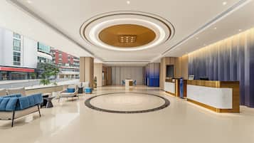 A modern hotel lobby with a reception desk, seating area, and a circular decorative floor feature.
