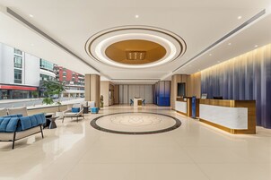 Un moderno vestíbulo de hotel con mostrador de recepción, zona de estar y un llamativo elemento decorativo circular en el suelo.