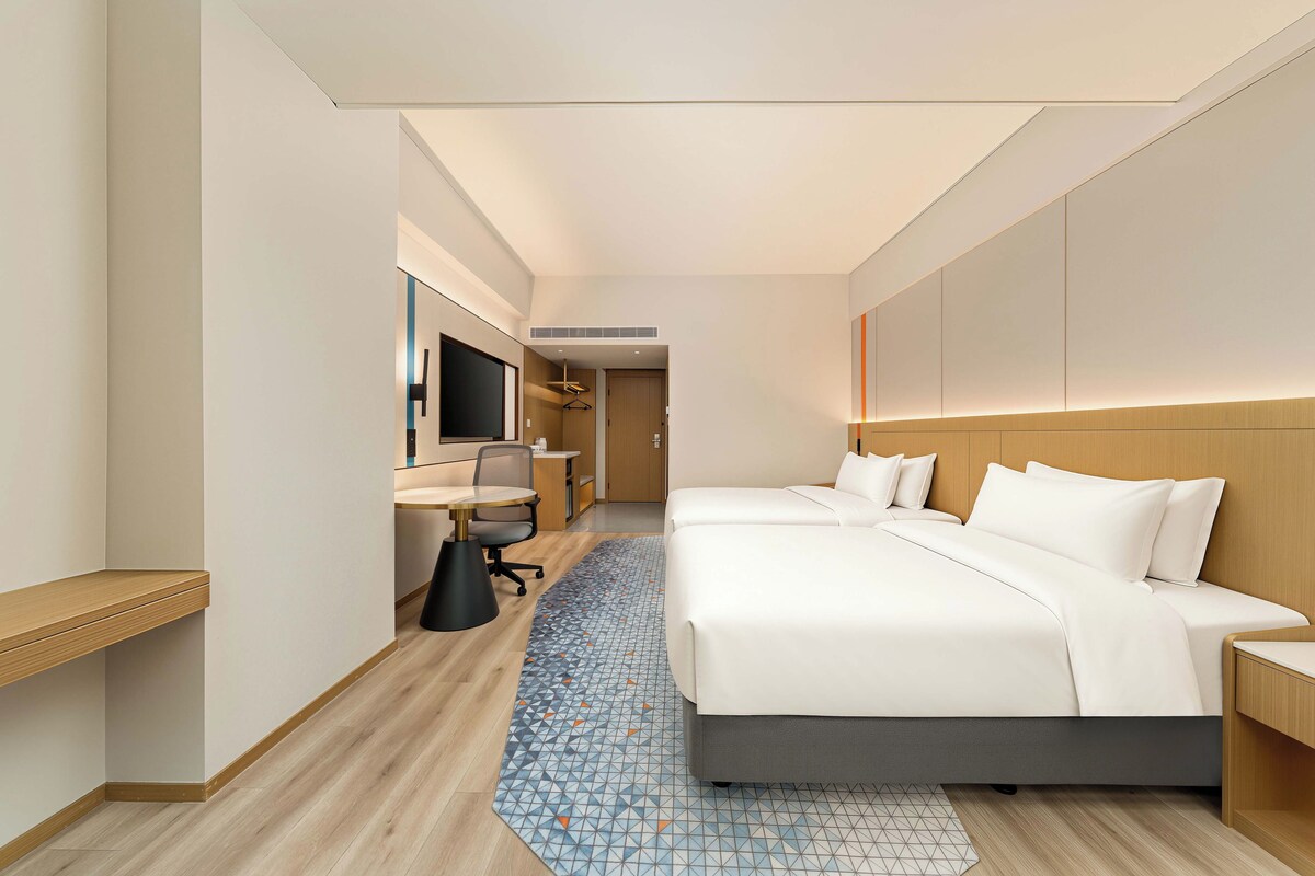 Habitación de hotel con una cama grande, un escritorio con silla, un televisor y un armario.