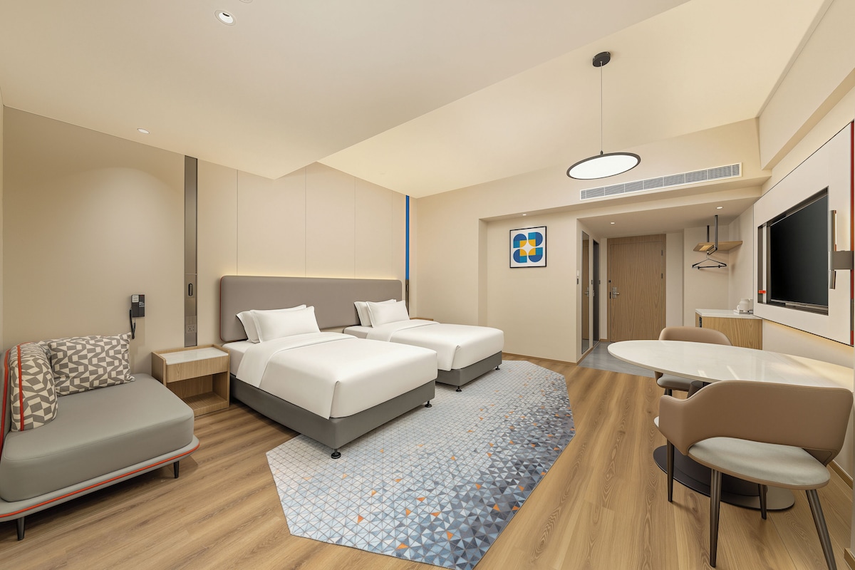 Una habitación de hotel con una cama, un sofá, un escritorio y una silla.