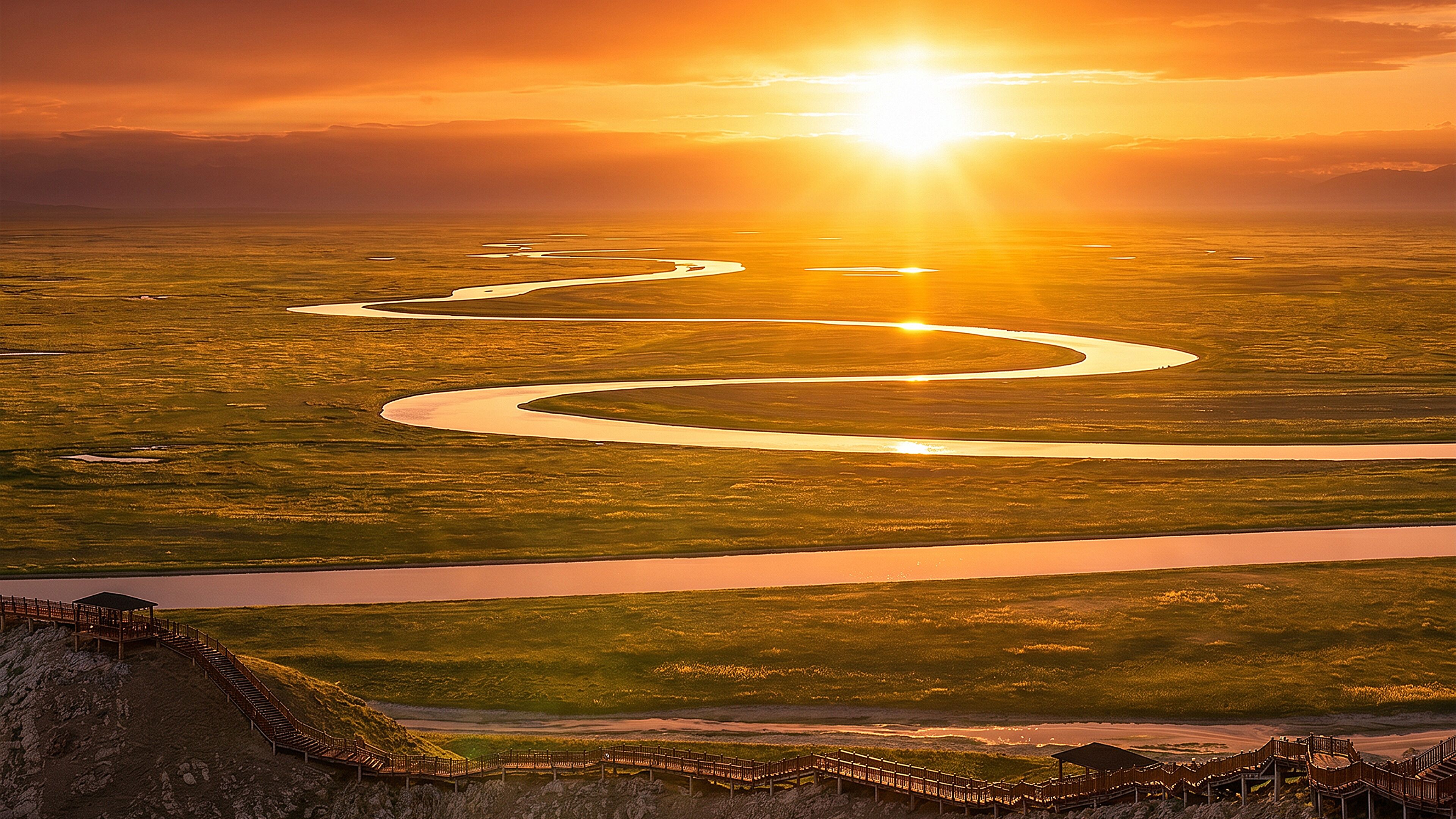 A river meandering through a landscape with a wooden bridge and a viewing platform.