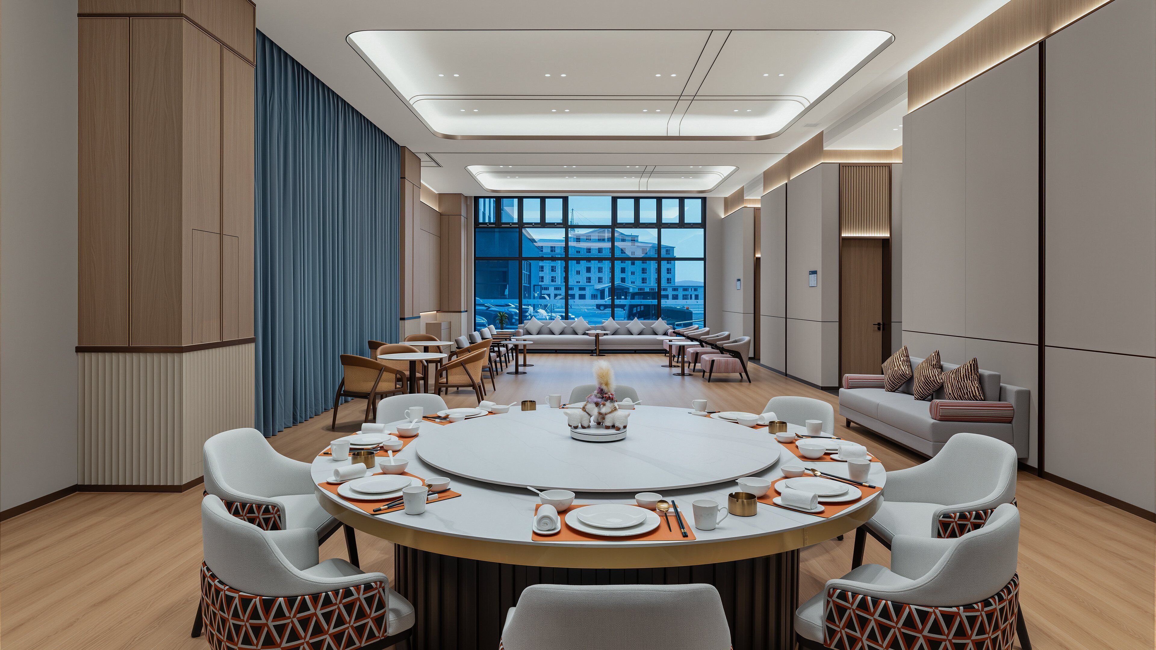 Un espace repas moderne avec une table ronde dressée pour un repas, entourée de sièges confortables.