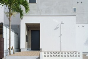 Un edificio moderno con una puerta oscura, exterior de color claro y una ventana pequeña.