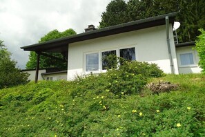 A single-story house with a sloped roof, a satellite dish, and a window.