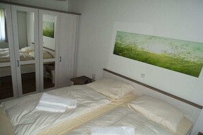 Ein Schlafzimmer mit einem Bett, einem Kleiderschrank und einem Bild an der Wand.