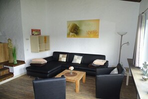 A living room with a black sofa, a wooden coffee table, and a Buddha statue.