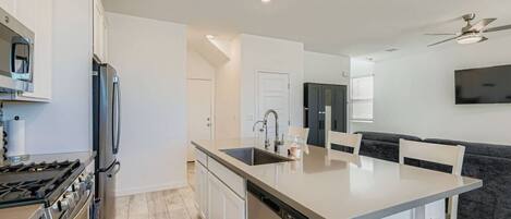 Een moderne keuken met een centraal eiland, ingebouwde apparatuur, en een zithoek met een bank en stoelen.