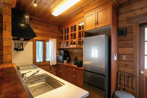 A wooden cabin interior with a kitchen featuring a stainless steel refrigerator, wooden cabinets, and a built-in microwave. - Private rental type log BASE / Kaga City Ishikawa (Kaga City)
