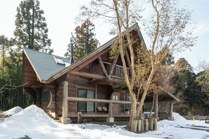 Une cabane en rondins avec un toit en pente, de grandes fenêtres et une véranda.