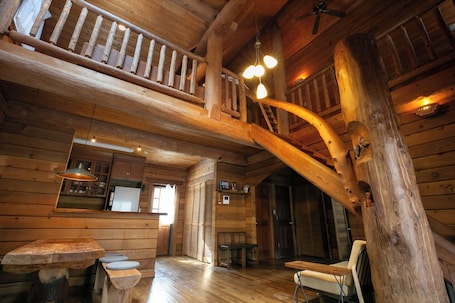A wooden interior with a staircase, wooden walls, a dining area with benches, and a kitchen area.. Private rental type log BASE / Kaga City Ishikawa