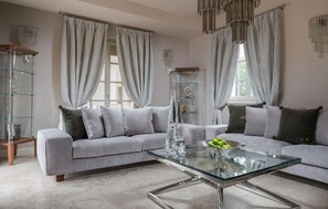 Ein modernes Wohnzimmer mit einem Glastisch, grauen Sofas und einer Vitrine aus Glas.