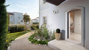 Uma casa moderna de dois andares com um jardim bem cuidado, uma escadaria visível e fachada limpa e branca.