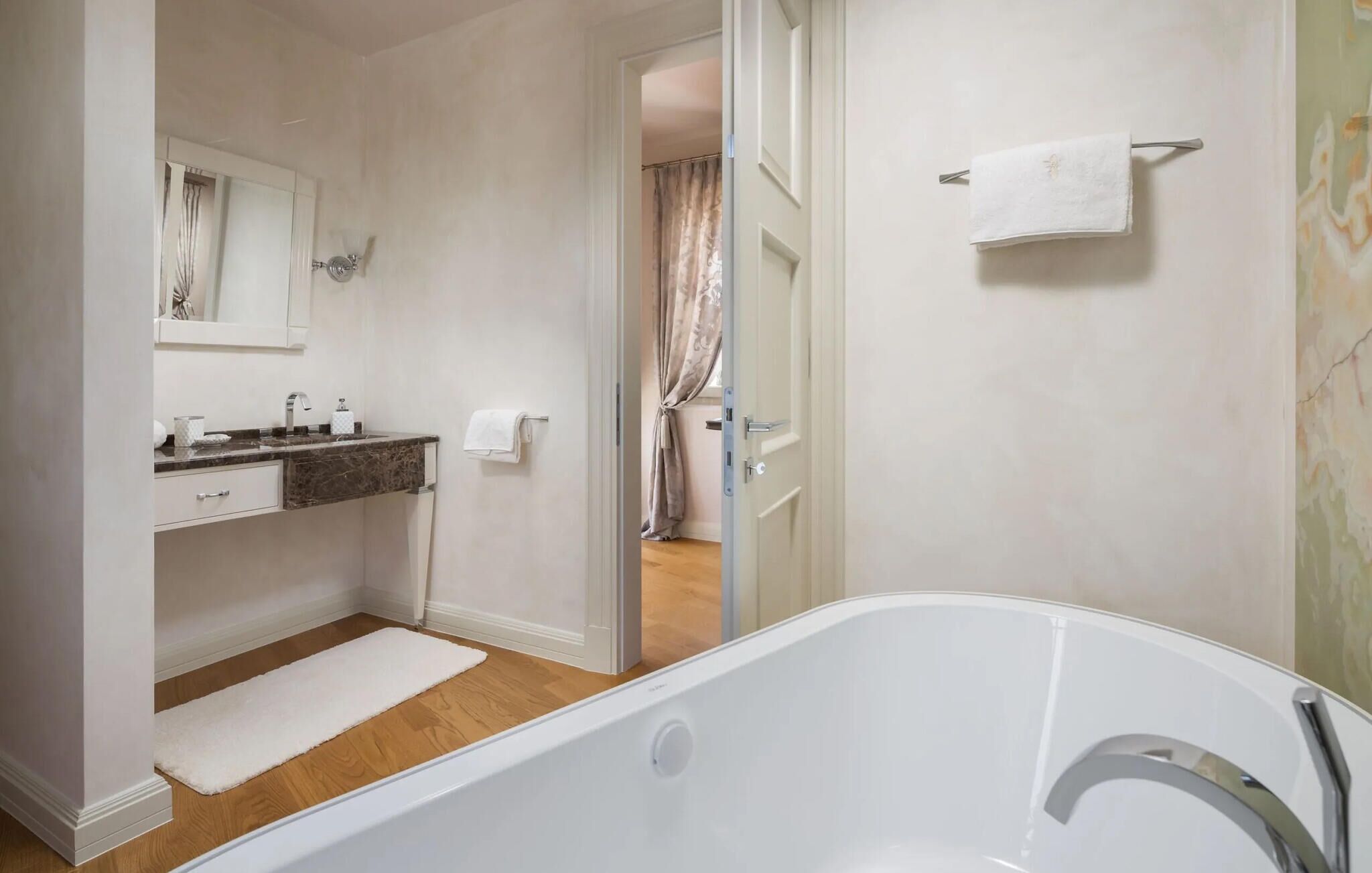A bathroom with a bathtub, a sink with a marble countertop, and a mirror.