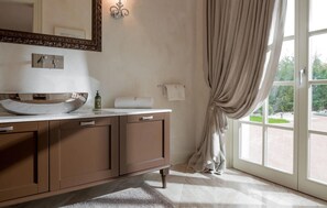 Ein Badezimmer mit Marmorwaschbecken, einem großen Spiegel, einem Handtuchhalter und Blick durch ein Fenster.