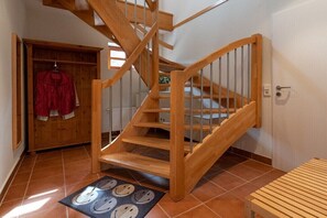 Eine Holztreppe mit Handlauf, eine Holztür und ein Fliesenboden.