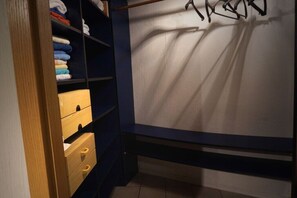 Ein Schlafzimmer mit einem Bett, einem Kleiderschrank und einem Regal mit gefalteten Handtüchern.