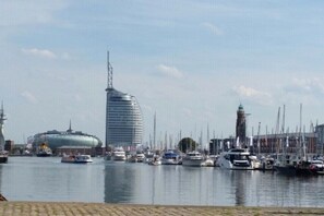 A marina with boats, a distinctive modern building, and a historic tower. - New Koralle Port in Bremerhaven (Bremerhaven)