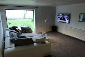 Ein Wohnzimmer mit einer Couch, einem Fernseher und einem Fenster.