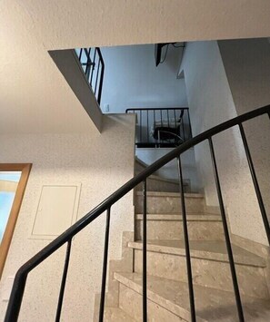 Eine Treppe mit Metallgeländer, die zu einer oberen Etage führt.