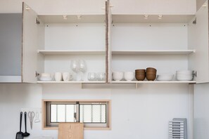 Eine Küche mit offenen Schränken, einem Fenster und Küchenutensilien.