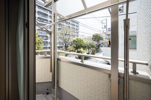 Ein Balkon mit Blick auf ein Wohngebäude und Bäume.