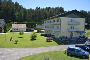 Um hotel com vários andares, varandas, área de estacionamento e um gramado bem cuidado.