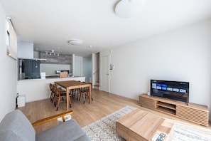 Ein modernes Wohnzimmer mit Essbereich, einer Küche und einem Fernseher.