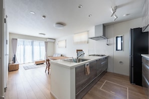 Eine moderne Küche mit einer zentralen Kochinsel, integrierten Geräten und einem Essbereich mit Sofa und Tisch.