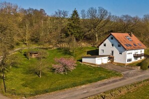 Ein zweistöckiges Haus mit Satteldach, Garage und einem umzäunten Garten.