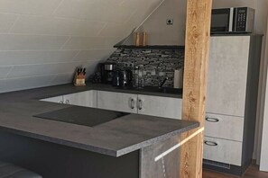 Eine moderne Küche mit Steinrückwand, integriertem Herd und einer Mikrowelle in einem Schrank.