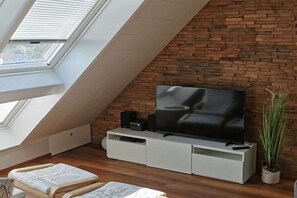 Ein modernes Wohnzimmer mit Fernseher, weißem Unterhaltungsschrank und einer Ziegelwand.