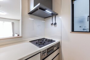 A modern kitchen with a gas stove, stainless steel range hood, and a window with a view of the outside.