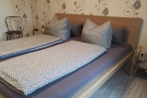 Ein Schlafzimmer mit Bett, Kissen, einem Sessel und einem kleinen Tisch.