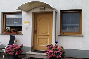 Ein Gebäude mit einer Holztür, einer kleinen Veranda und zwei Fenstern.
