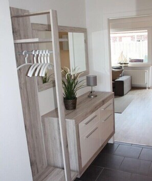 A modern bathroom with a wooden vanity, a mirror, a plant, and a towel rack. - Holiday home in Hage with swimming pool (Hage)