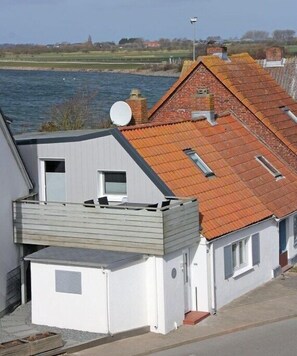 Ein Wohngebäude mit Schrägdach, Satellitenschüssel und Blick auf das Wasser.