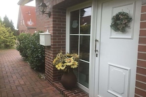 A brick house with a white door, a mailbox, and a vase of sunflowers. - Holiday apartment with 2 bedrooms (Ostgroßefehn)