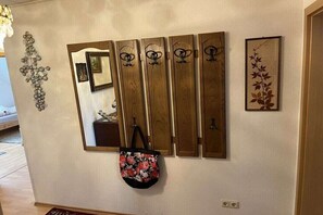 A wall with a mirror, a decorative metal piece, and a framed artwork. - Holiday apartment with 2 bedrooms (Ostgroßefehn)