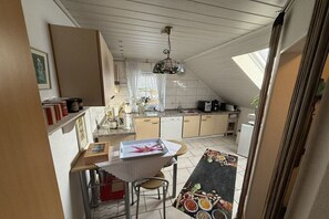 A kitchen with a dining area, a ceiling fan, and a window with curtains. - Holiday apartment with 2 bedrooms (Ostgroßefehn)
