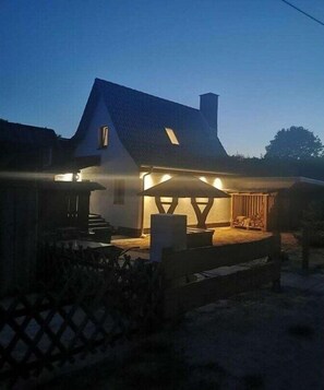 Ein Haus mit Veranda, einer Treppe und einem gut beleuchteten Außenbereich.