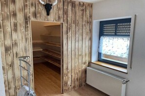 Una stanza con una parete in legno, una finestra con persiane, un termosifone e una scala in metallo.
