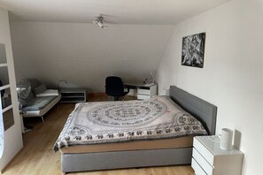 Ein Schlafzimmer mit Bett, Schreibtisch, Stuhl und einem Wandbild.