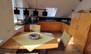 Eine kleine Küche mit Essbereich, Holzschränken, einem Fenster und einem eingebauten Backofen.