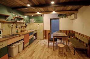Une cuisine avec des meubles de rangement en bois, un évier et un coin repas comprenant une table et des bancs.