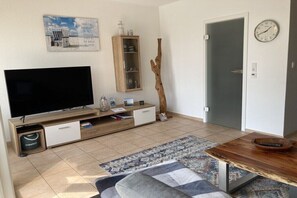 Ein modernes Wohnzimmer mit Flachbildfernseher, Holzunterhaltungseinheit und einer Tür mit Uhr.