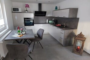 Eine moderne Küche mit Essbereich, einer Mikrowelle, einem Backofen, einer Kaffeemaschine und einer Kerze.