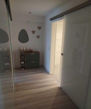 Ein Zimmer mit Holzboden, einem Kleiderschrank, einer Kommode und Wanddekorationen in Herzform.