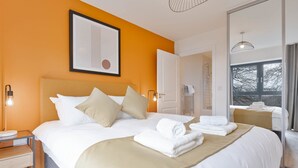 Hotellihuone, jossa on suuri sänky, yöpöytä lampun kanssa, seinällä oleva kehystetty kuva ja ikkuna, josta on näkymä.
